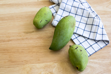 Whole Green Mango on a wooden table.In selective focus.