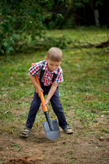 funny boy with shovel in garden
