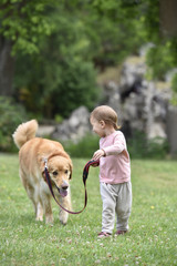 baby girl giving a walk to dog at the park