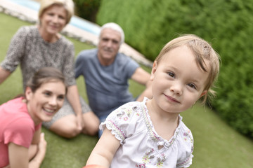 Fototapeta na wymiar Portrait of cute 2-year-old girl, family in background