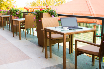 Laptop, mobile phone, glasses and coffee on a wood table in street cafe