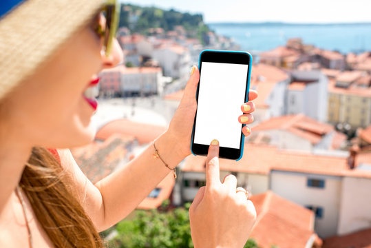 Female hands holding phone with white screen on the old city background