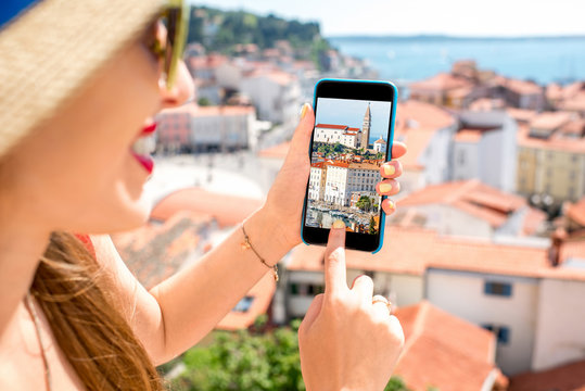 Young fwmale traveler photographing with smart phone Piran old town. Close up view focused on the phone screen