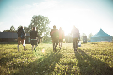 Travelers walking on green field at sunset.