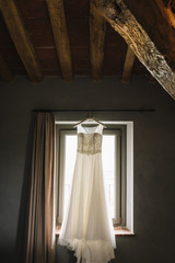 Abito da sposa appeso a una finestra in una casa antica
