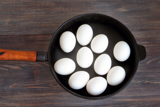 You can't make omelet without breaking eggs. Metaphor. White whole (unbroken) eggs on a cast iron pan