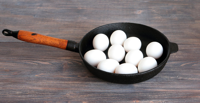 You can't make omelet without breaking eggs. Metaphor. White whole (unbroken) eggs on a cast iron pan