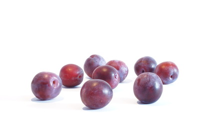 Спелые красные сливы лежат на белом фоне
