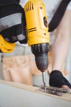 Carpenter tightening screw to hinges on a wooden door