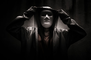 A stranger woman wearing hoodie with white mask hiding in the dark,Scary background for book cover - 116787134