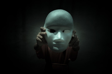 Mysterious person showing white mask in the dark,Scary background for book cover