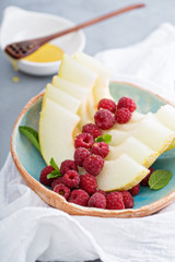 Melon slices served with raspberry and honey