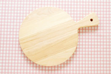 Empty round wooden chopping board on pink tablecloth, background