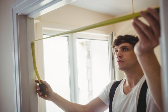 Carpenter Measuring A Door Frame