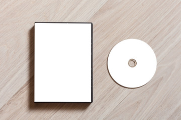 Dvd or cd disc cover case mockup. Template with plastic box and disc with white isolated free space for design. Mock up with black package for compact or dvd disc. On wooden table background - obrazy, fototapety, plakaty