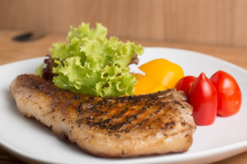 Grilled Pork serve with colorful salad on wooden table