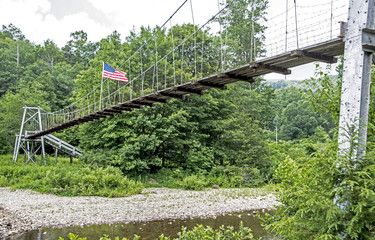 Obraz premium Swinging bridge crosses over a river.