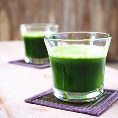 A glass of healthy mixed green vegetable juice on a wooden background