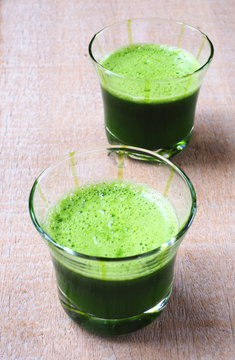 A glass of healthy mixed green vegetable juice on a wooden background