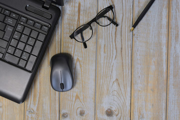 Wooden desk table with laptop computer,  fountain pen, mouse and glasses with empty copy space