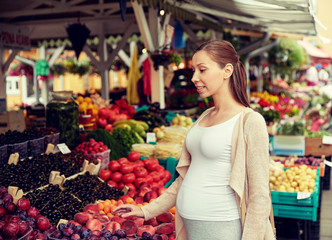 pregnant woman choosing food at street market