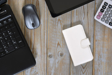 Close up of a wooden table bureau at the office with laptop, computer, smart phone case,...