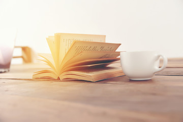 white cup of the coffee and vintage book. Photo with filter as a