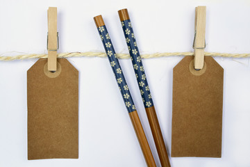 White background with sisal rope and clothes pins with empty copy space tags and wooden chopsticks
