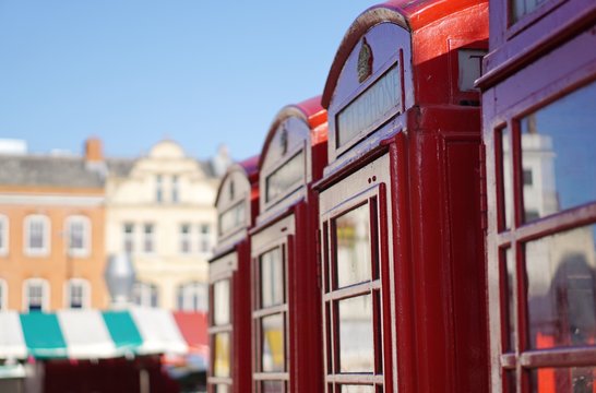 Row of four British red telephone boxes near Market Square in Cambridge, England. Shallow depth of field.