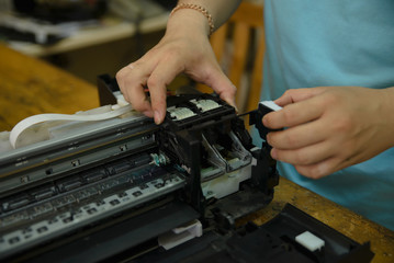 Close-up on the hands of computer repairman,solving problem in printer.