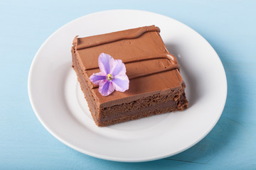 Piece of chocolate cake on white plate on blue background