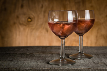 Glasses with rose wine on rustic wood background
