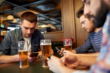 men with smartphones drinking beer at bar or pub