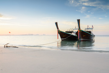 Two wooden boats on a beach at sunrise time