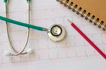Stethoscope and medical electrocardiogram , ECG diagram , notebook and pencil