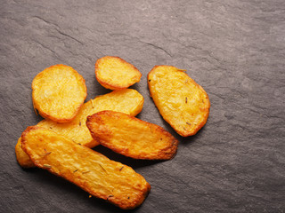 Roasted potato wedges on dark slate