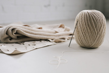 A ball of string or thread and a metal crochet hook or needle with folded fabric. 