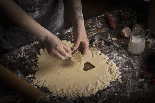 Valentine's Day baking, woman cutting out heart shaped biscuits from dough.