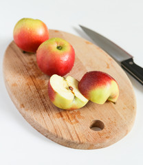 Juicy red apples lie on wooden board with a knife next to it in top view