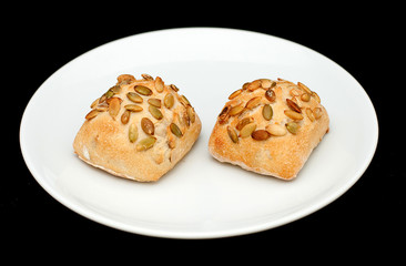 Two sandwich buns with pumpkin seeds on white plate