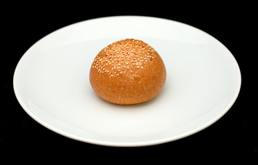 Sandwich bun with sesame on white plate 