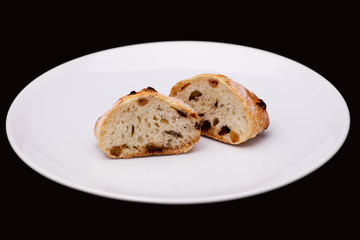 Two half of sandwich bun with raisins on white plate 