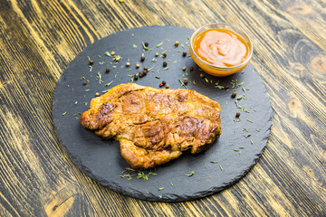 Grilled pork steak on a wooden table.