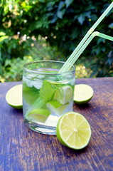 Nutritious detox water with lime and mint in a glass on the wood background