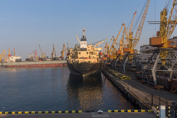 Cargo ship is unloaded at the dock at the port. Industry