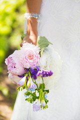 Букет невесты из розовых пионов и белой гортензии с нежно-голубыми лентами в руке у невесты