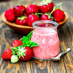 Beautiful appetizer red strawberry fruit smoothie or milk shake in glass jar with berries on wooden background, top view. Yogurt cocktail. Close up. Natural detox. Liquid ice cream.
