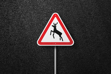 Road sign triangular shape with a picture of the deer on a background of asphalt. The texture of the tarmac, top view.