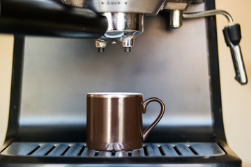 espresso machine making coffee and pouring in a brown  cup