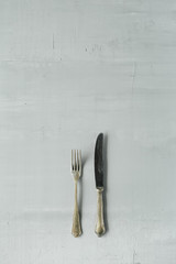 flat lay of golden fork and knife on grey concrete background. top view